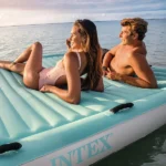 Two people lounging on an inflatable pool mat, enjoying a relaxing time on the water