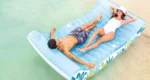 Two people lounging on an inflatable water lounge with floral design, relaxing on the water