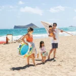 Family on the beach carrying the Dino Buddies 3-Ring Baby Pool, ready for a fun day by the water