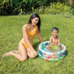 Mother and child enjoying playtime in the Dino Buddies 3-Ring Baby Pool in a garden setting