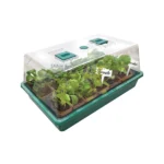 Compact greenhouse with seedlings under a clear propagation dome, ideal for indoor and outdoor gardening.