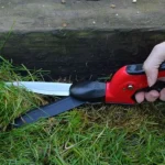 Darlac Swivel Shears in action, trimming grass along the edge of a log with precision using adjustable swivel blades.